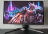 Aorus FO27Q3 gaming monitor, sat atop a black surface, against a grey background, with a bird-style mech on its screen.