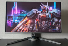 Aorus FO27Q3 gaming monitor, sat atop a black surface, against a grey background, with a bird-style mech on its screen.