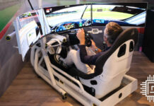 A person sat in Corsair's racing sim prototype, in a triple monitor setup