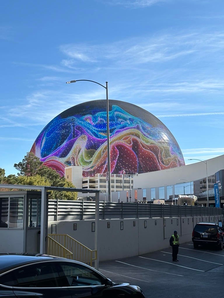 Las Vegas Sphere, in daylight, with a multi-coloured ribbon-like effect on its screen