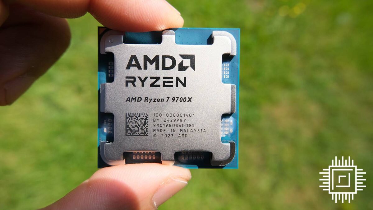 A picture of an AMD Ryzen 7 9700X CPU in the hand, in front of grass.