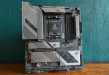 ASRock X870E Taichi Lite motherboard, standing upright on a wooden surface, against a green background.