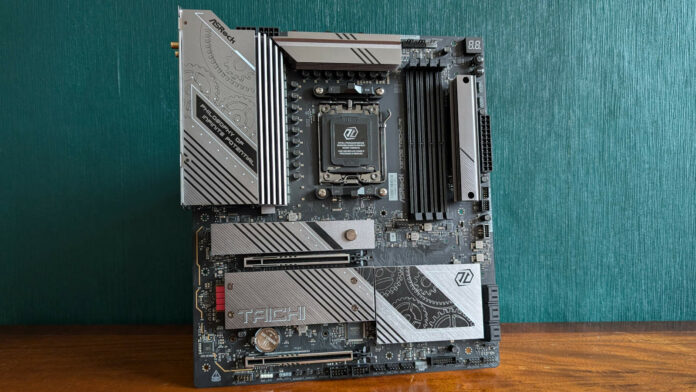 ASRock X870E Taichi Lite motherboard, standing upright on a wooden surface, against a green background.