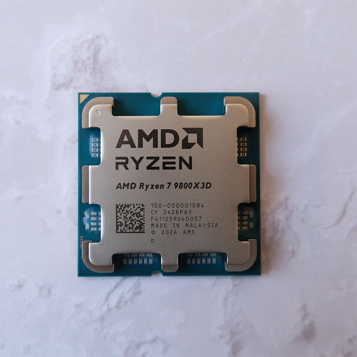 A picture of the AMD Ryzen 7 9800X3D CPU from top down.