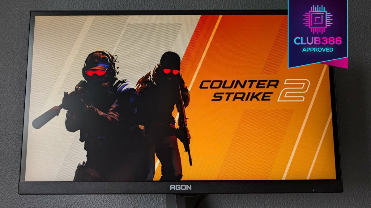 AOC Agon Pro AG246FK displaying a wallpaper from Counter-Strike 2, with Club386 'Approved' award in top-right.