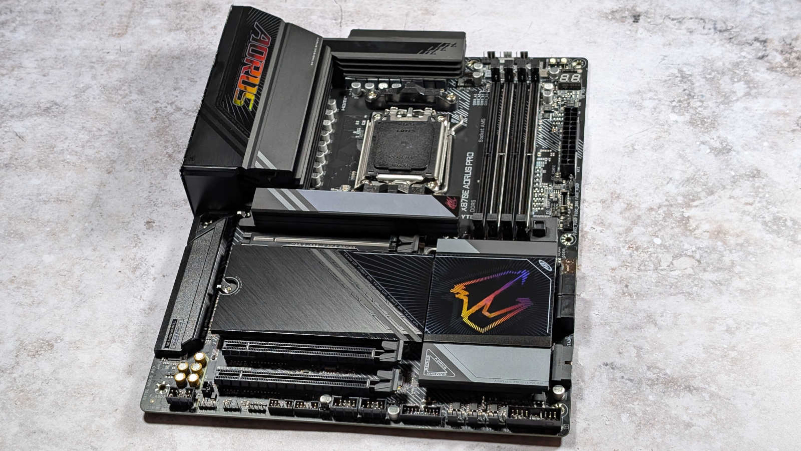 Wide shot of X870E Aorus Pro against a white stone surface.