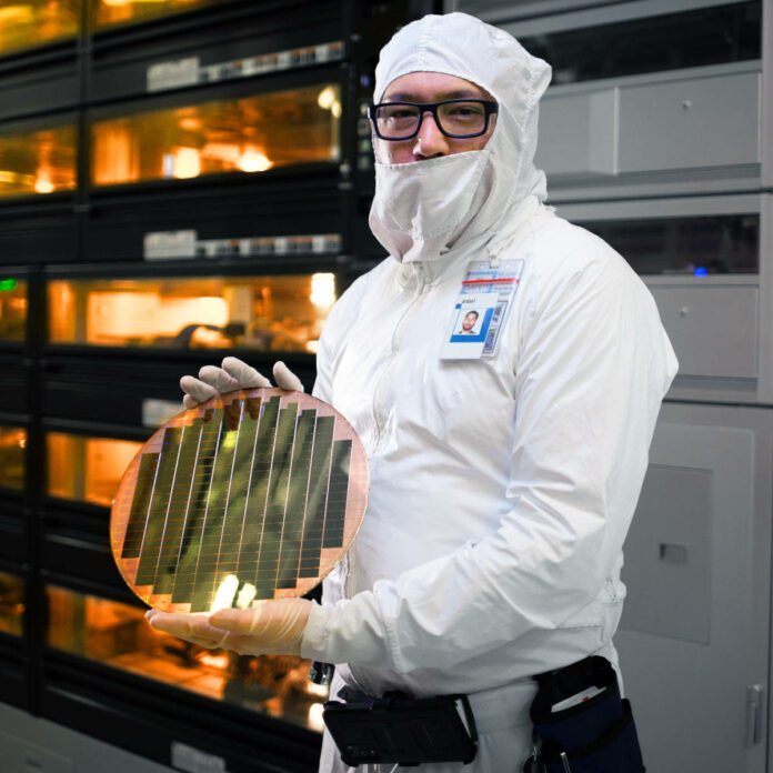 An Intel factory employee holds a wafer with 3D stacked Foveros technology at an Intel fab in Hillsboro, Oregon, in December 2023.