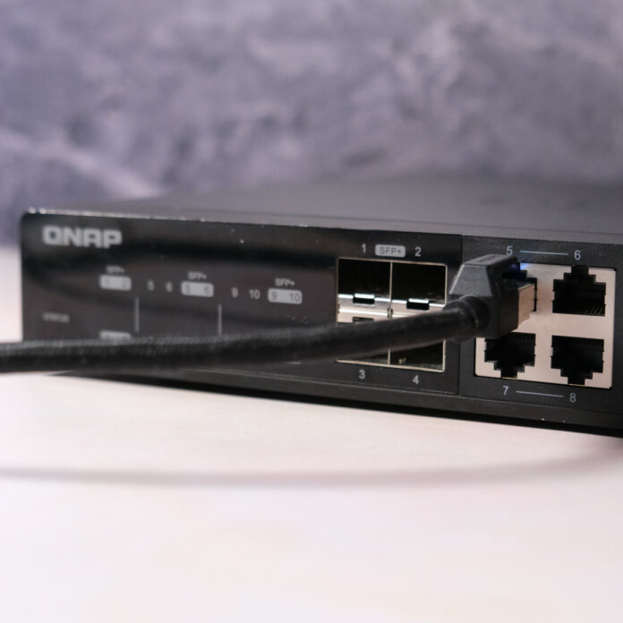 QNAP 10Gb/s network switch with one Ethernet cable poking out.