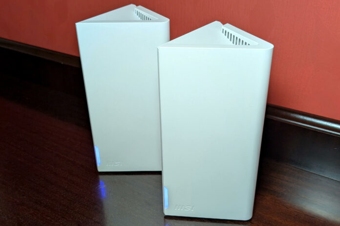 Two MSI Roamii BE Lite modules standing side-by-side on a wooden countertop, against red wallpaper.