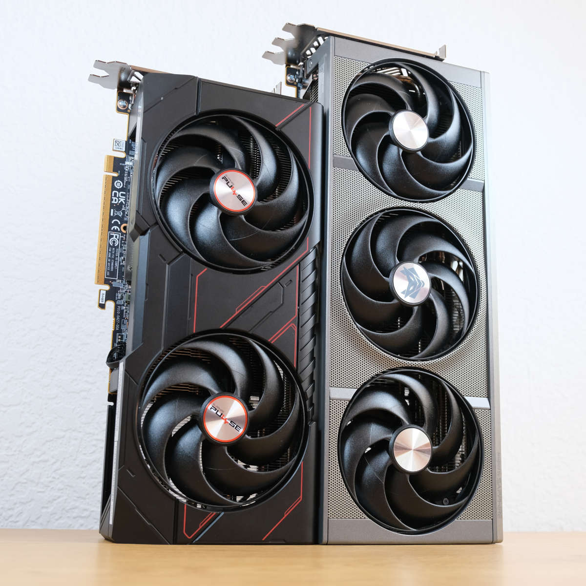 Sapphire Pulse Radeon RX 9070 (left) and Sapphire Nitro+ Radeon RX 9070 XT stand upright next to each other.