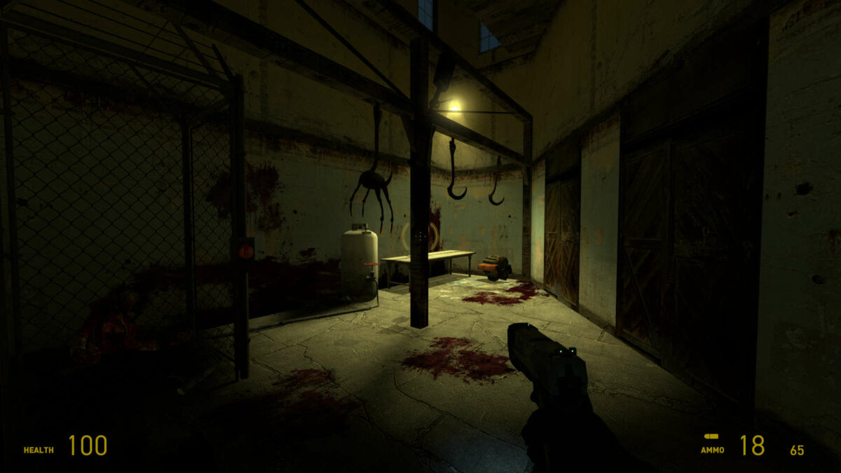 A dimly lit room, with a headcrab hanging from a hook and zombie in the left corner, in Half-Life 2.