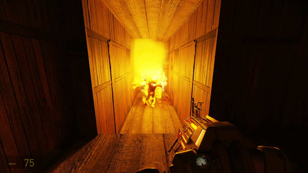 A headcrab zombie aflame walks down a dark corridor, lighting it up with its fire, in Half-Life 2 RTX.